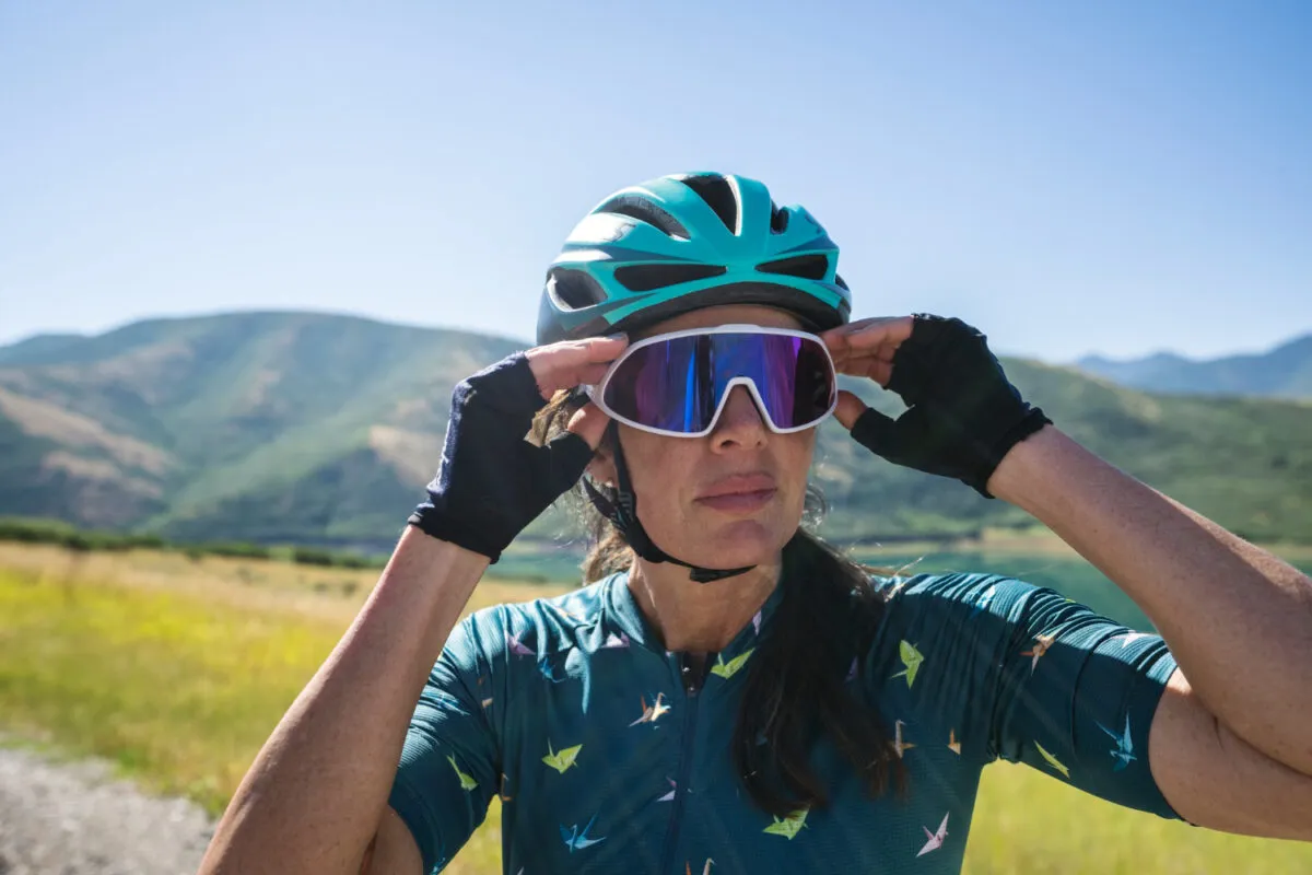 Atleta de ciclismo em ambiente natural ajustando óculos de sol.