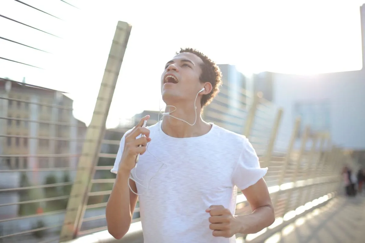 Homem correndo em ambiente urbano usando fones de ouvido brancos durante o treino