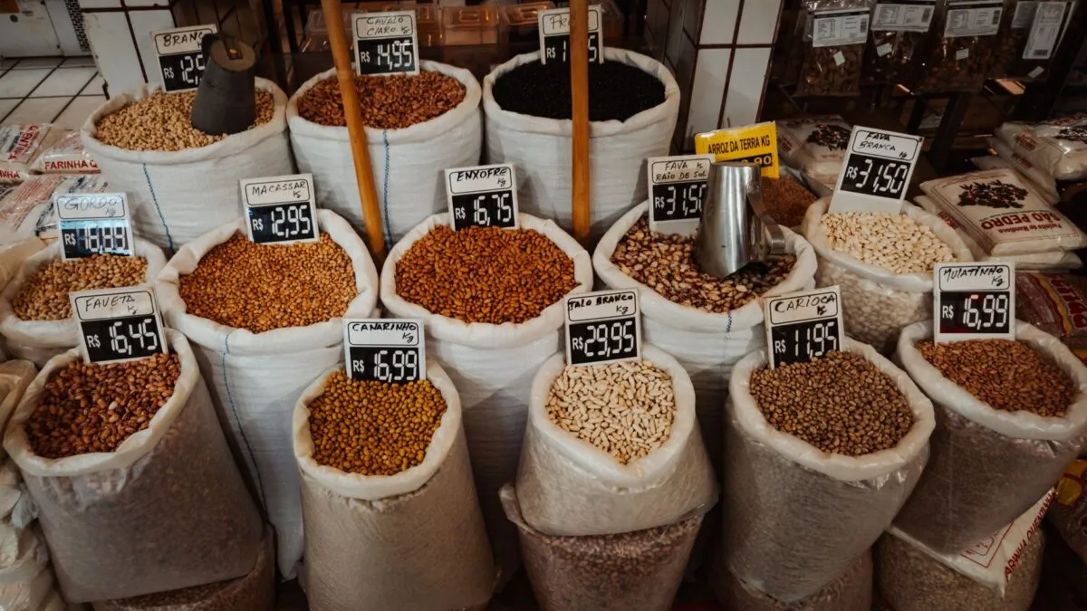 Sacos abertos de feijões e grãos com etiquetas de preço em uma barraca de mercado, alimentos ricos em proteína de origem vegetal